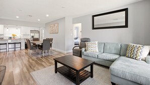 A modern living room with a sofa, coffee table, and dining area. - 🌴 Tropical 3BR Retreat | Huge Screened Patio | Private Yard  | Beaches & D... (Fort Lauderdale)