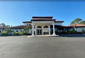 Una entrada cubierta con un toldo blanco y columnas, que conduce a un edificio con techo de tejas rojas.