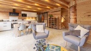 A modern interior with wooden beams, a kitchen, dining area, and seating.