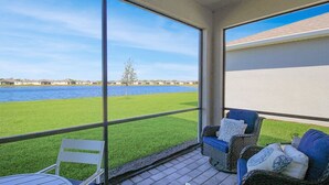 Un balcone con vista su un lago, arredato con sedie in vimini e un tavolino.