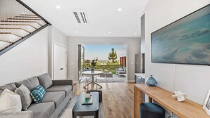Una sala de estar moderna con una escalera, un comedor y vistas al exterior.