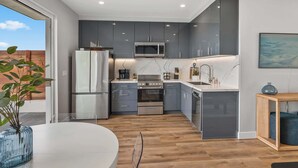 Una cocina moderna con armarios grises, un refrigerador de acero inoxidable, un microondas y un horno empotrado.