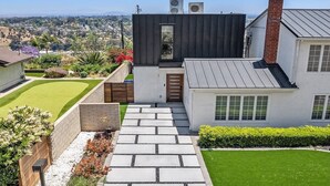Una casa moderna con un sendero de piedra que lleva a la entrada, rodeada de jardines cuidados y una vista despejada del paisaje urbano.