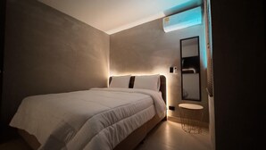 Une chambre à coucher moderne avec un grand lit, des tables de chevet et un climatiseur fixé au mur.