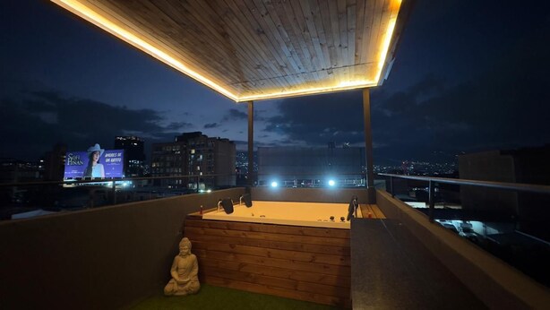 Une terrasse sur le toit, avec une plateforme en bois, une statue de Bouddha et un panneau publicitaire en arrière-plan.