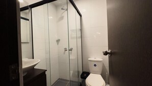 Une salle de bain moderne avec une douche à parois de verre, un lavabo blanc et des toilettes.