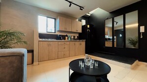 Une cuisine moderne avec des meubles en bois, un réfrigérateur noir et un coin repas comprenant une table ronde et des chaises.