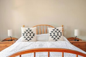 A bed with a wooden headboard, two bedside tables, and two lamps.
