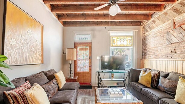 A living room with two sofas, a coffee table, a television, and a door with a stained glass window.