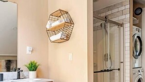 A bathroom with a wooden vanity, a glass shower enclosure, and a washing machine.