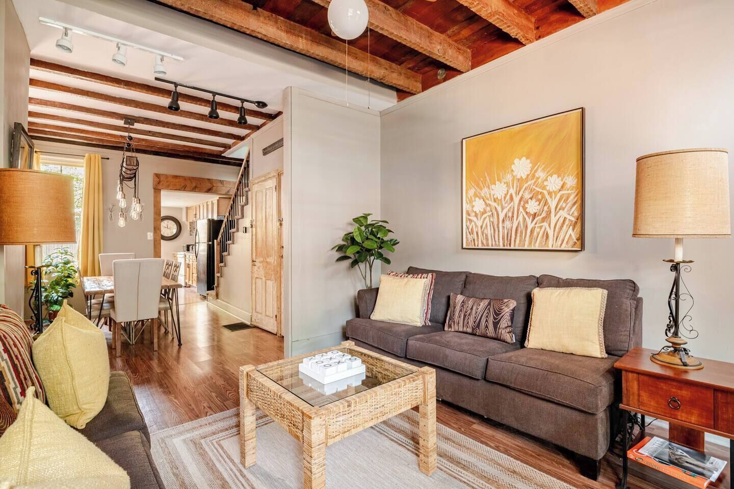 A living room with a sofa, coffee table, and lamp. There is a staircase leading to another room.