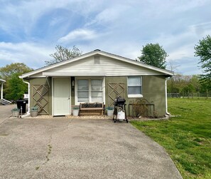 A single-story building with a front porch, a bench, and a small garden area.