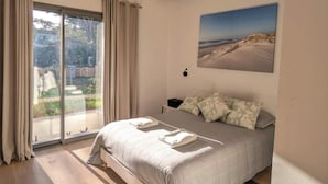 Ein modernes Schlafzimmer mit einem großen Bett, Blick ins Freie und einer Pendelleuchte.