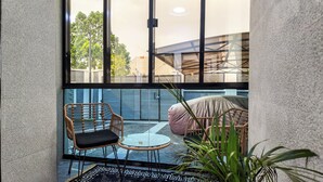 A small, enclosed patio area with wicker furniture and a glass table.