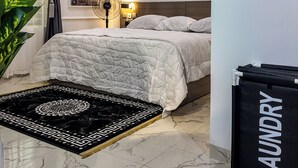 Une chambre moderne avec un lit, une table de chevet, une œuvre d’art murale, un luminaire au plafond et un chariot à bagages noir.