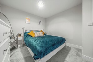 Ein Schlafzimmer mit einem Bett, einer weißen Kommode und einem Nachttisch.