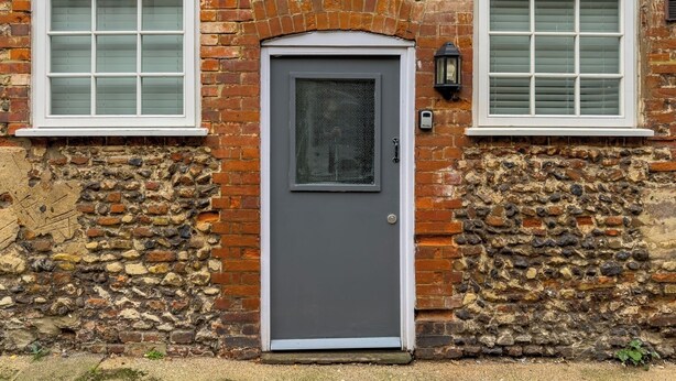 A building with a stone facade, a grey door, and two windows with white frames. - College Lane Apartment, Bury St Edmunds (Bury St Edmunds)