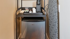 Una cocina compacta con cafetera, un certificado enmarcado y un casco en un soporte de pared.