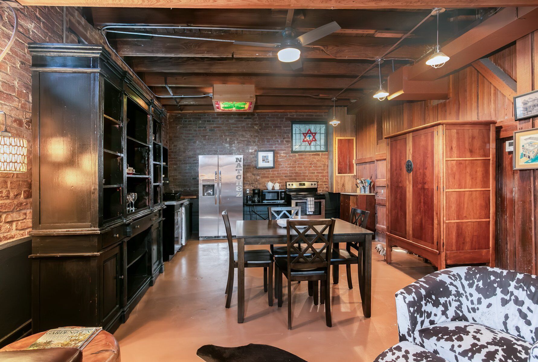 A cozy restaurant with a brick wall, wooden ceiling, and a dining area with a table and chairs.