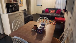 Un salon chaleureux avec une table en bois, des chaises, un canapé et une machine à café.