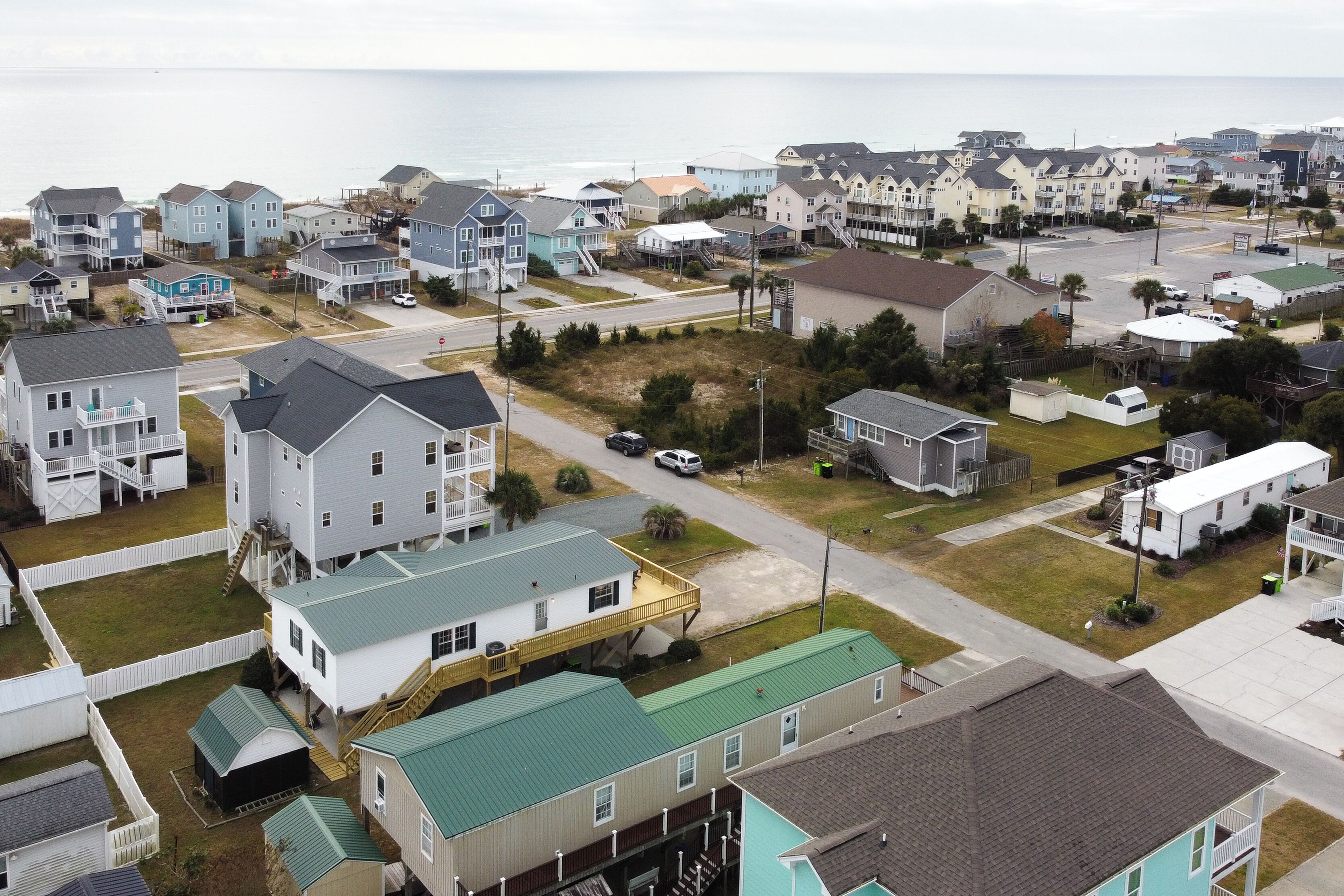 A coastal residential area with multiple two-story houses, some with balconies, and a road in the foreground.