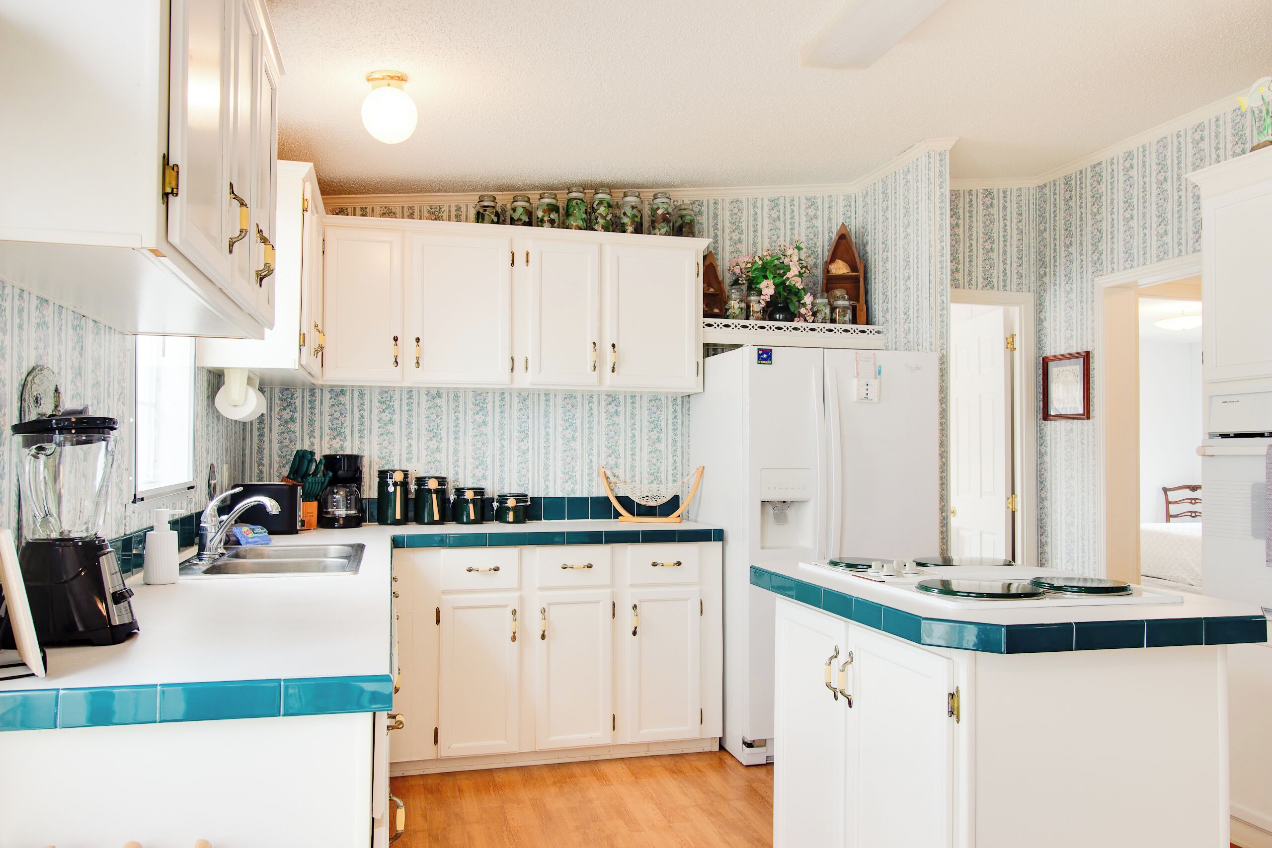 A kitchen with white cabinets, a sink, and a countertop with a blender and coffee maker.
