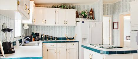 A kitchen with white cabinets, a sink, and a countertop with a blender and coffee maker.