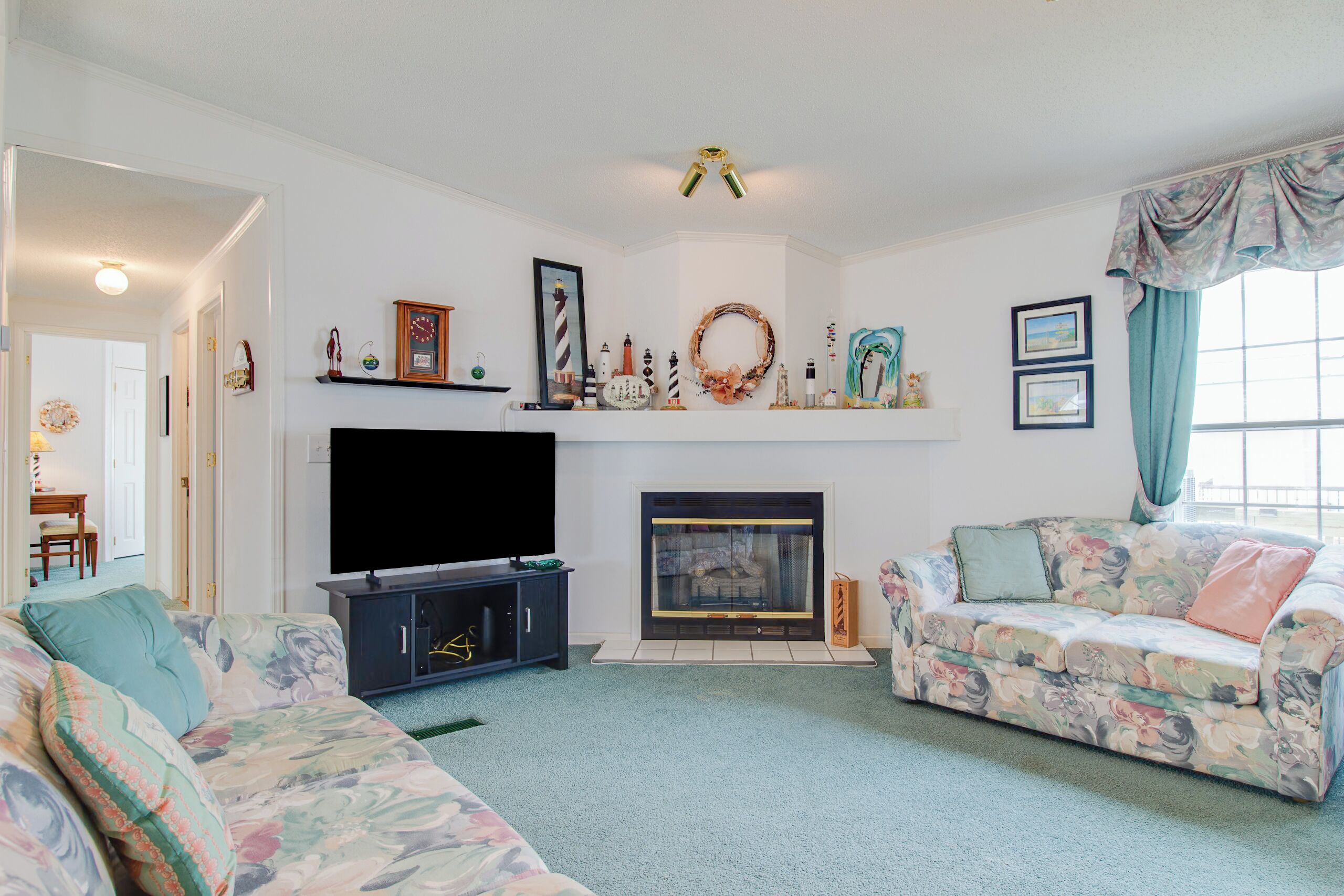 A living room with a fireplace, two sofas, a TV, and various wall decorations.