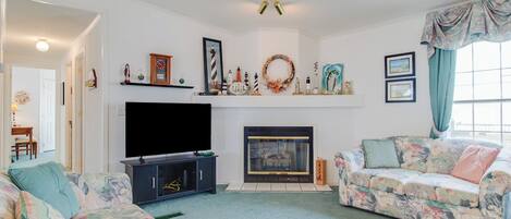 A living room with a fireplace, two sofas, a TV, and various wall decorations.