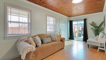 A spacious living room with a brown sofa, a white armchair, and a large plant.