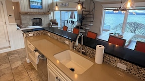Une cuisine moderne dotée d’un grand îlot central, d’une cheminée et offrant une vue sur l’extérieur.