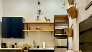 A compact bedroom with a bed, bedside tables, and a small kitchenette. - Wild Western Property (Huntsville)