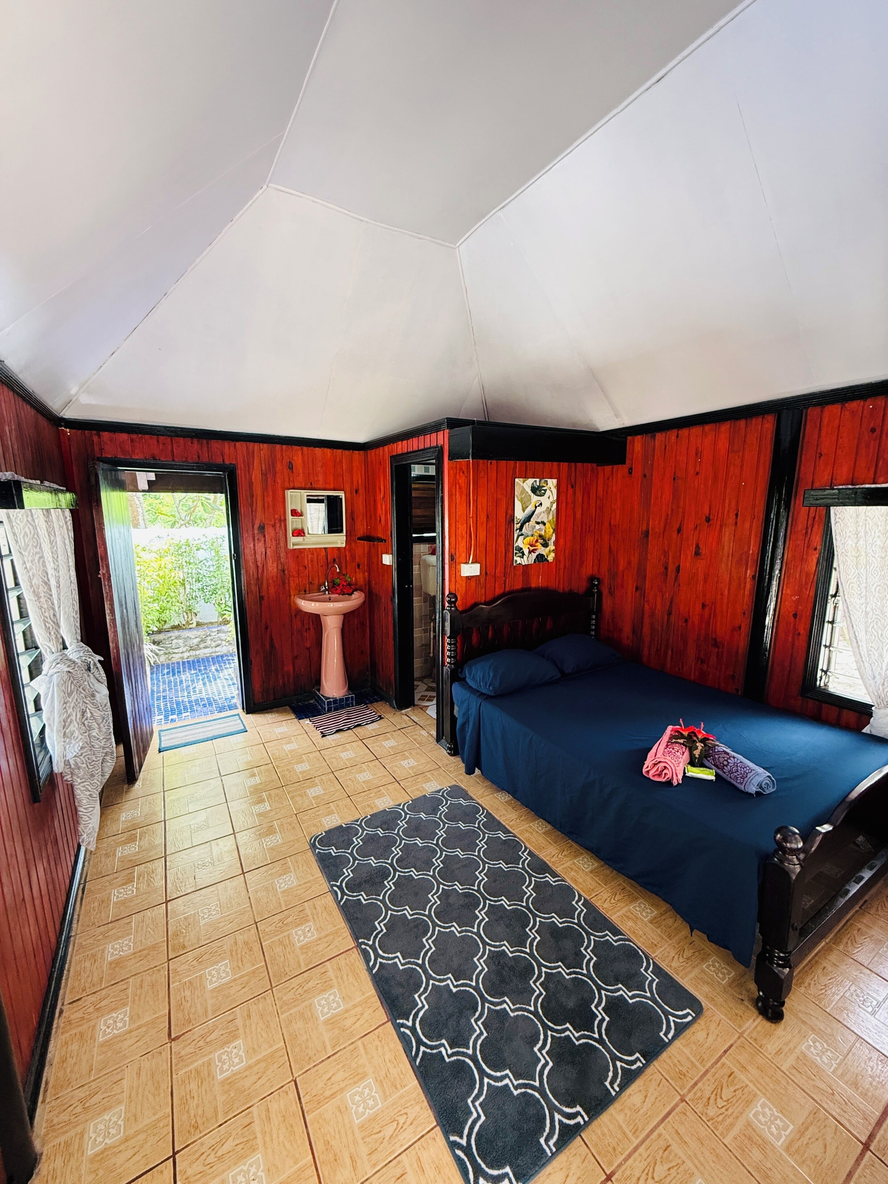 A room with a bed, a sink, and a door leading outside.