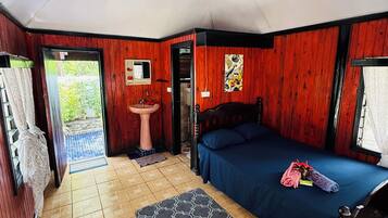 A room with a bed, a sink, and a door leading outside.