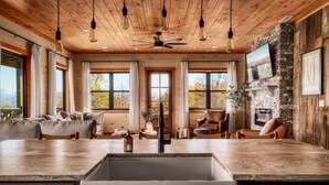 Un'ampia cucina con una grande isola, soffitto in legno e un camino in pietra.