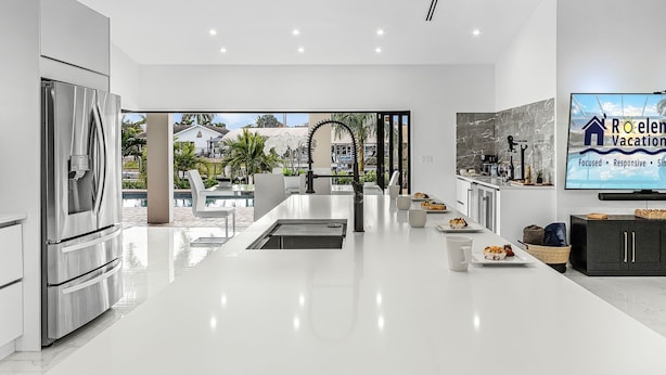 A modern kitchen with a large island, stainless steel appliances, and a view of the outdoors. - Sunshine, Serenity & a Heated Pool Escape for All-Day Fun – Modern Vibes Villa - Roelens (Cape Coral)