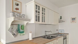 Una cocina con armarios blancos, encimera de madera, pileta doble y estufa.
