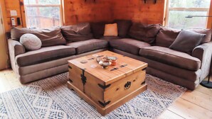 Un salon chaleureux avec un canapé d’angle en cuir marron, une table basse en bois et un tapis à motifs.