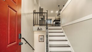 A staircase with a red door, a welcome sign, and a kitchen area in the background. - Family Arcade Retreat + Fire Pit + 4BR Near RMNP (Loveland)