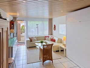 A modern living room with a sofa, a dining table, and a chair. - Center Communal D1 by Interhome (Laax)