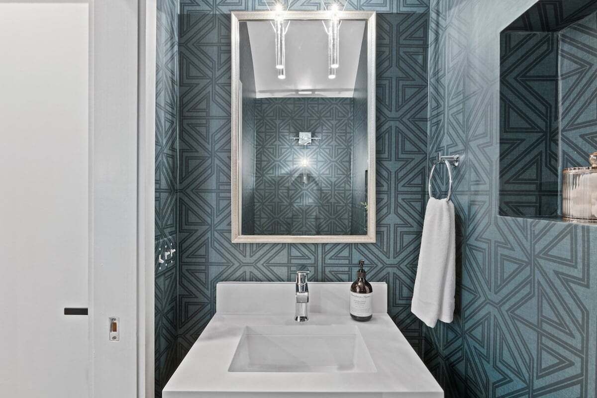 Une salle de bain avec un lavabo blanc, un miroir et une serviette accrochée au mur.