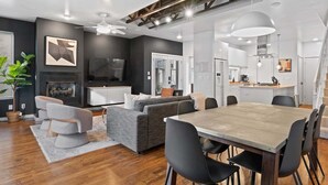 A modern living room with a dining area, a fireplace, and a kitchen in the background. - Urban Retreat @ Cherry Street (Tulsa)