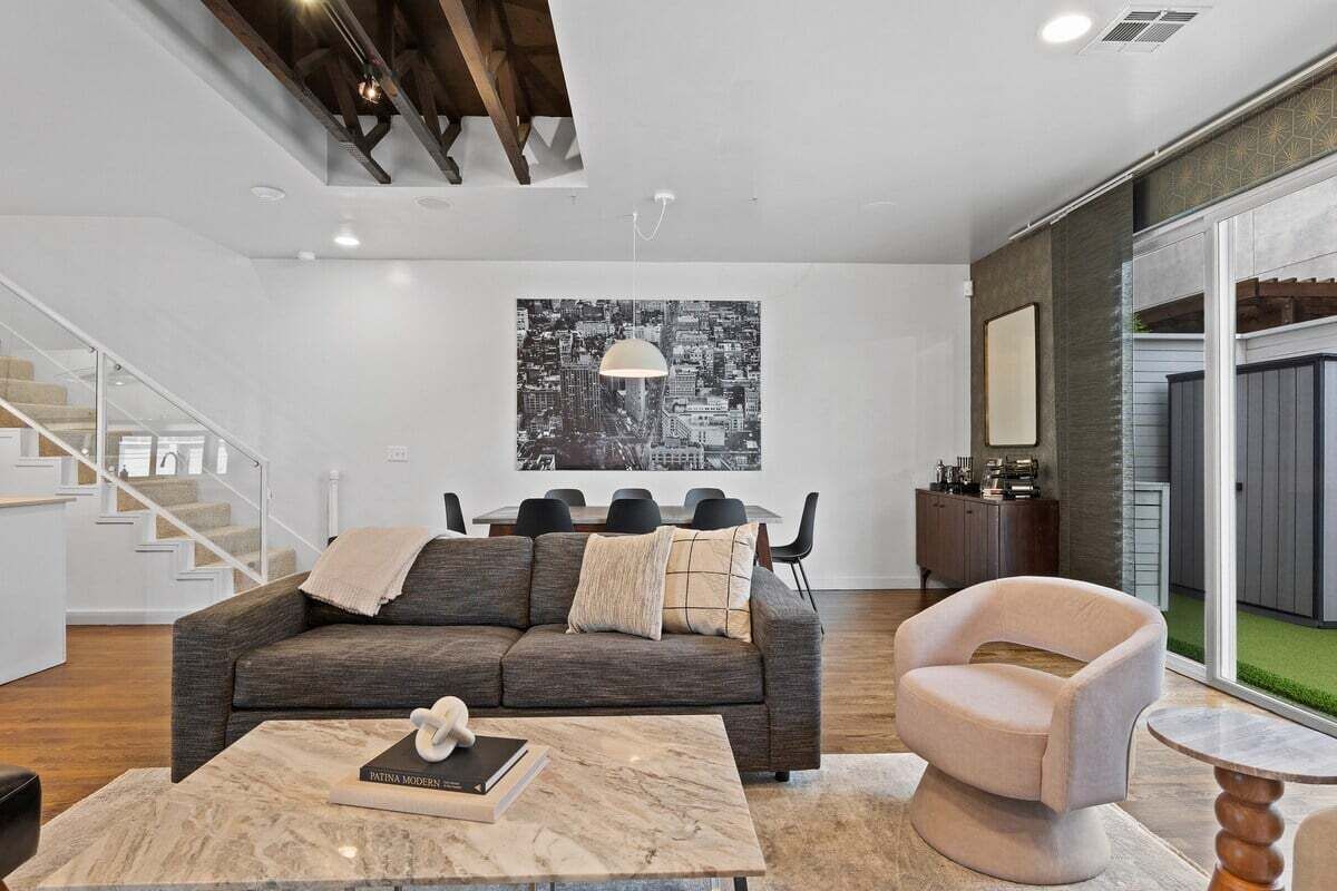 Een moderne woonkamer met een grijze bank, een ronde tafel en een stadsgezicht op de muur.