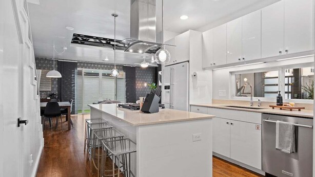 A modern kitchen with white cabinetry, a central island, pendant lighting, and a stainless steel dishwasher. - Urban Retreat @ Cherry Street (Tulsa)