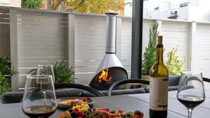 An outdoor dining area with a grill, wine bottles, and a charcuterie board. - Urban Retreat @ Cherry Street (Tulsa)