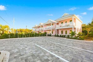 Ein Hotel mit großzügigem Parkplatz, mehreren Balkonen und einem gepflegten Garten.