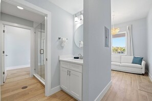 Ein modernes Badezimmer mit Glasdusche, weißen Schränken und einem großen Spiegel.