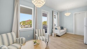 Ein modernes Wohnzimmer mit einem runden Holztisch, gestreifte Sofas, einem weißen Sofa und einer Kronleuchter.