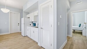 Eine moderne Küche mit weißen Schränken, einer eingebauten Mikrowelle und einem Kühlschrank.
