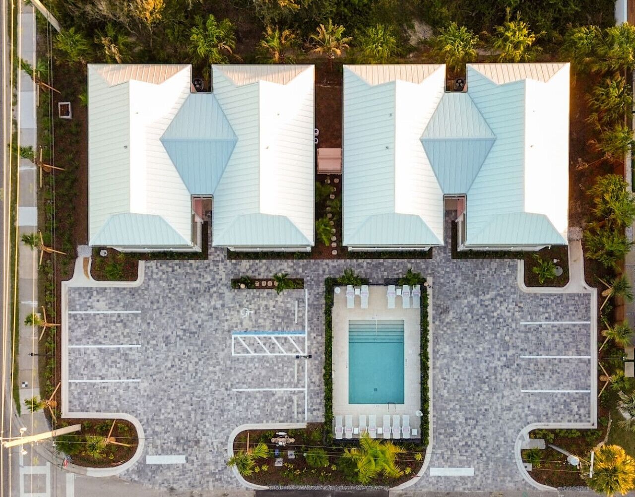 A top-down view of a hotel with two large buildings, a swimming pool, and a parking area.